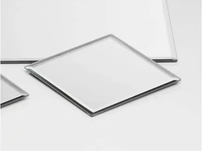 Several square mirrored tiles are arranged on a white surface.