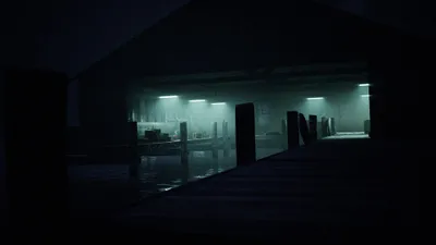 A dark, atmospheric scene of a dock or boathouse at night, with artificial lights illuminating the water and structures.