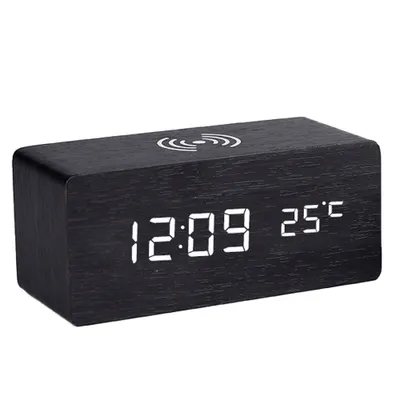 A black wooden digital alarm clock with a wireless charging symbol on top and a digital display showing the time and temperature.