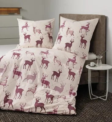 A bed with a duvet cover and pillow set featuring a deer pattern, placed in a bedroom setting.