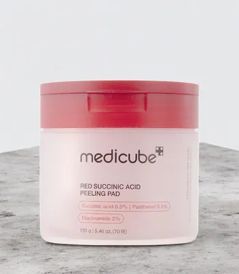 A product shot of a skincare jar on a textured surface.