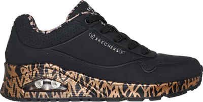 A side view of a black Skechers sneaker with gold and brown animal print accents on the sole and heel.