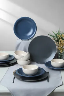 A collection of ceramic plates and bowls arranged on a table with a runner.