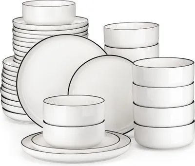 A collection of white ceramic plates and bowls with black trim, neatly stacked and arranged.