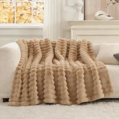 A plush beige blanket draped over a sofa in a living room setting.