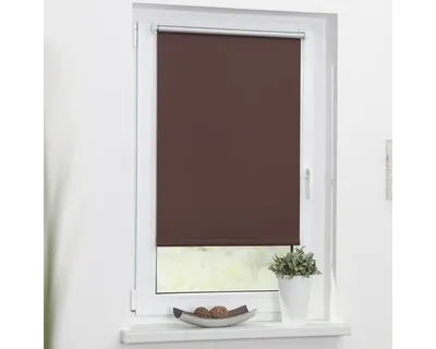 A brown roller blind is installed on a white window frame.