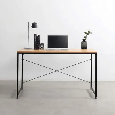 A modern desk with a laptop, books, a lamp, and a vase with a plant.