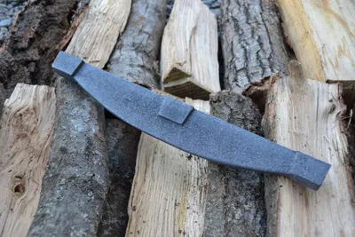 A metal tool resting on a pile of firewood.