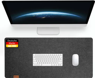 A computer monitor and a desk mat with a keyboard and mouse on it.