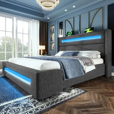 A modern bedroom with a gray upholstered bed featuring blue LED lighting.