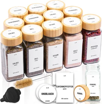 A collection of spice jars with bamboo lids and labels, along with accessories like a brush and funnel, arranged on a white background.
