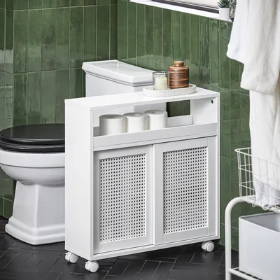 A bathroom scene with a toilet, a white storage unit with sliding doors, and green tiled walls.