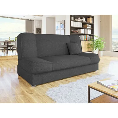 A dark gray sofa bed is shown in a well-lit living room with wooden floors and a white rug.