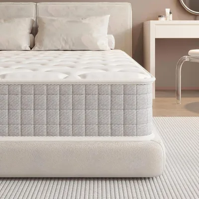 A close-up view of a mattress on its base, with pillows visible in the background.