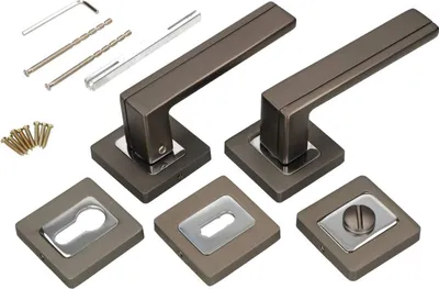 A set of door handles and associated hardware, including screws and drill bits, laid out on a white background.
