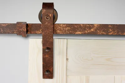 A close-up view of a sliding barn door hardware set mounted above a wooden door.