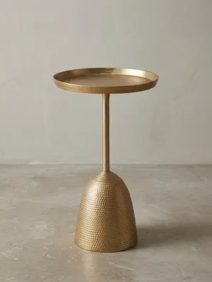 Design Beistelltisch in Gold aus einer 3/4-Perspektive, die die runde Tablett-Tischplatte und den skulpturalen, gehämmerten Standfuß aus Metall hervorhebt._#sku_BARWL6.670#