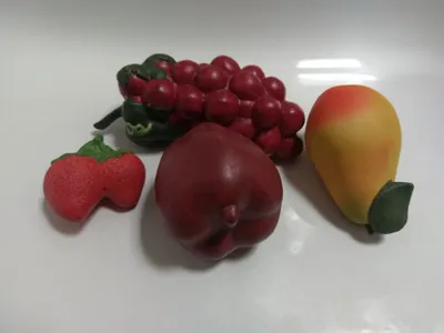 Eine kleine Sammlung künstlicher Früchte: eine Traube, einen Apfel, eine Birne und zwei Erdbeeren.