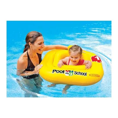 A woman is in a swimming pool with a baby in a yellow inflatable.