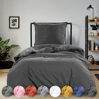 A bed with dark gray bedding is shown in a room with a plant and a shelf.
