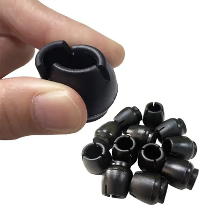 A hand is holding one of the black plastic stoppers while a pile of other stoppers are shown in the background.