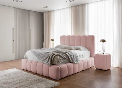 A bedroom scene with a pink upholstered bed as the main focus, flanked by a nightstand and wardrobe, with sheer curtains in the background.