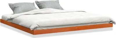 A bed with white bedding and gray pillows on a wooden frame, isolated on a white background.