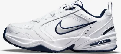 A white Nike Air Monarch IV shoe with navy accents is shown against a white background.
