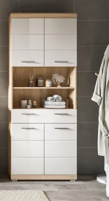 A tall, narrow bathroom cabinet with white high-gloss doors and wood-tone accents, set against a tiled wall.