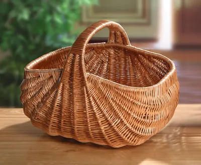 A wicker basket sits on a wooden surface with a blurred background of greenery and a doorway.