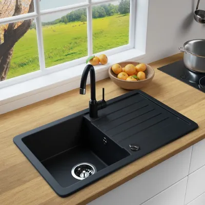 A black granite kitchen sink with a faucet, set on a wooden countertop with a window view of a green field.