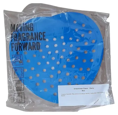 Ein blaues Urinalsieb in einer transparenten Plastikverpackung. Das Sieb ist herzförmig mit vielen Löchern und hat einen Kirschduft. Der Text 'MOVING FRAGRANCE FORWARD' ist auf der Verpackung zu sehen.