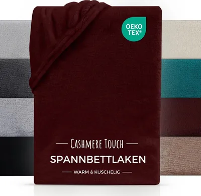 A folded burgundy fitted sheet is shown, with swatches of other colors of the same product visible on the left and right sides. A green OEKO-TEX logo is present.