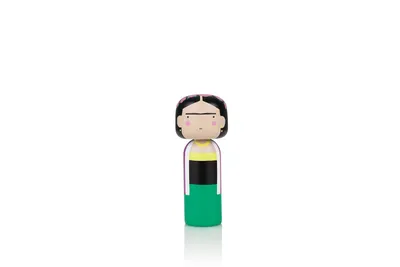 A small wooden doll representing Frida Kahlo stands against a white background.