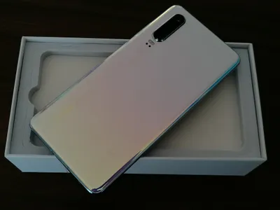 A white smartphone with an iridescent back is placed inside a white box.