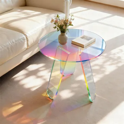 A round, iridescent acrylic side table with a book and a vase of flowers on it, placed next to a cream-colored sofa. Sunlight streams in, casting shadows on the floor.