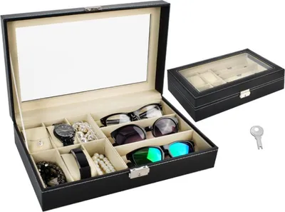 An open black jewelry and watch organizer box with a clear lid, displaying watches, sunglasses, and other accessories. A second, closed organizer box and a key are placed next to it.