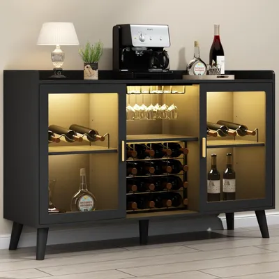 A black wine cabinet with glass doors, illuminated interior, and various bottles and glasses displayed. A coffee maker and a lamp are on top.