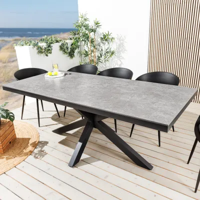An outdoor dining table and chairs set on a wooden deck overlooking the ocean.