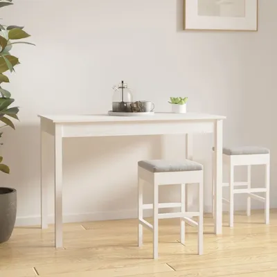 A white dining table with two white stools with gray seats in a room with a plant and a framed picture on the wall.