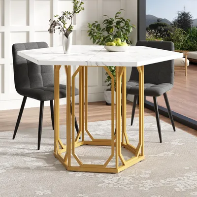 A hexagonal dining table with a marble-like top and gold geometric legs, set with two chairs in a dining room with a large window overlooking a scenic view.