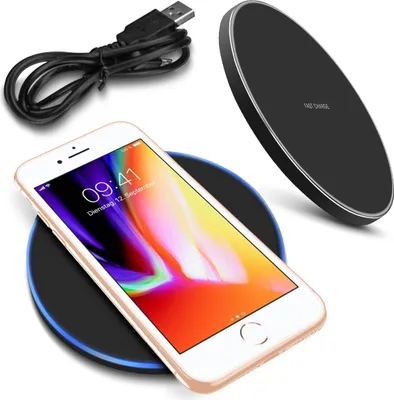 A smartphone is placed on a wireless charger, with a USB cable in the background.