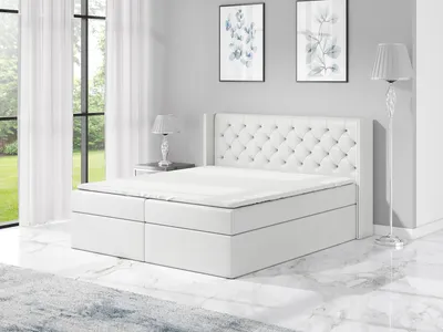 A white boxspring bed in a bedroom setting.