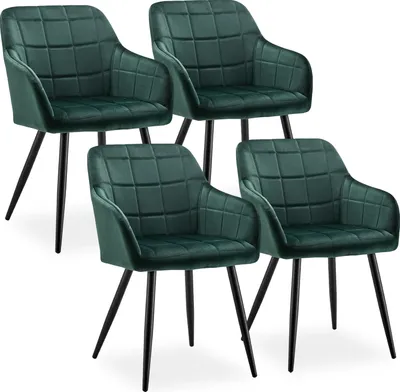 Four green velvet dining chairs with black metal legs are arranged in a staggered formation against a white background.