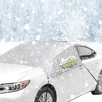 A white car is parked in a snowy environment, covered with a silver windshield cover.