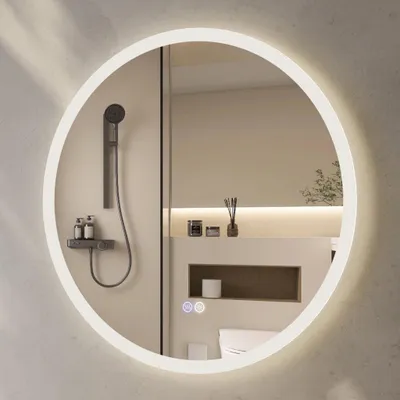 A round illuminated mirror in a modern bathroom setting, reflecting a shower and toiletries.