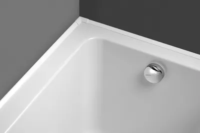 Close-up view of a white bathtub corner with a chrome drain.