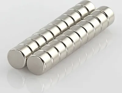 Two rows of cylindrical magnets are arranged diagonally on a white and light gray surface.