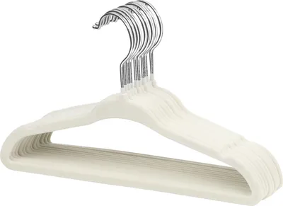 A stack of cream-colored velvet hangers with silver hooks.