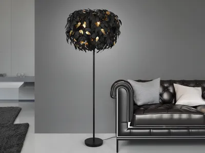 A black floor lamp with a feather-like shade is placed next to a black leather sofa in a modern living room.